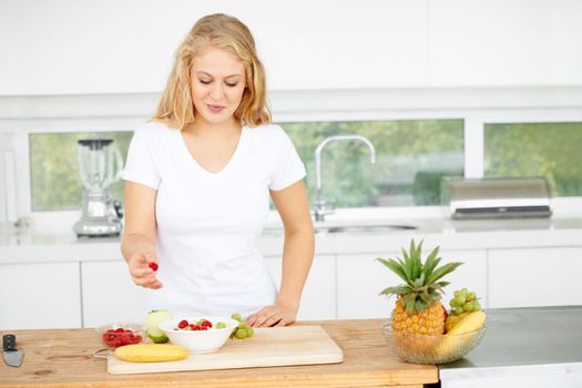 Satisfying her appetite with healthy alternatives. Curvaceous young woman eating fruit in her kitchen.