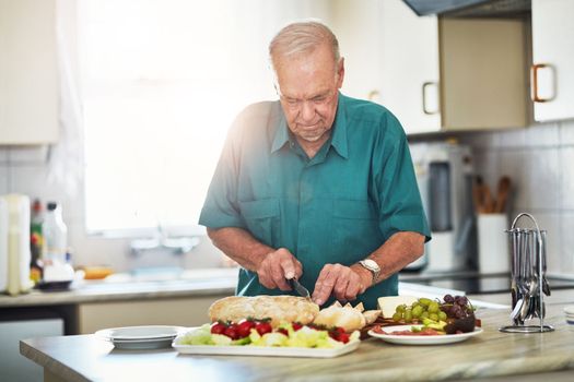 Retirement living at its finest. a senior man making lunch in his kitchen at home.