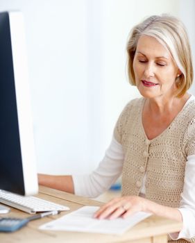 Mature woman calculating expenses using computer. Portrait of a mature woman calculating expenses using computer.