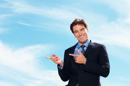 Business man showing something imaginary against cloudy sky. Handsome young business man showing something imaginary against cloudy sky.