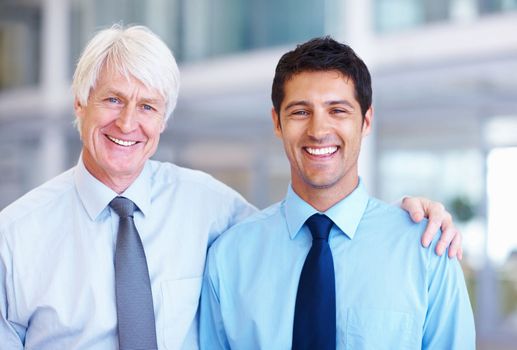 Smiling senior with junior executive. Portrait of friendly male executives smiling together at office.