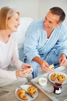 Mature couple having breakfast and looking at each other. Portrait of a smiling mature couple having breakfast and looking at each other.