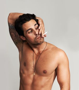 His habit has him in a tangle. A shirtless young man smoking a cigarette.