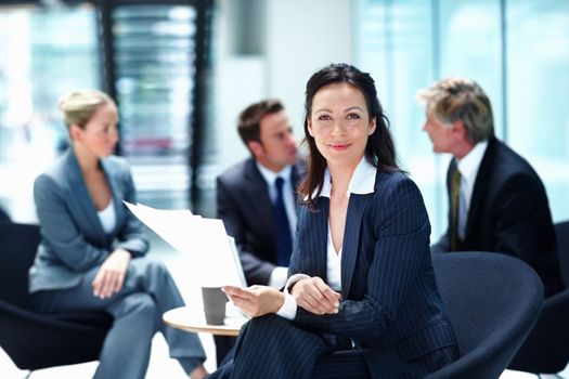 Smiling business woman with executives discussing. Portrait of business woman smiling with executives discussing in background.