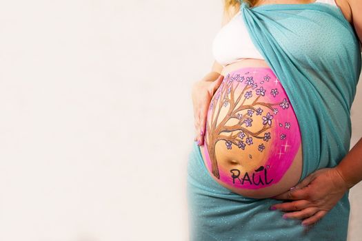 Eight months pregnant woman with bright dress and drawing on her belly