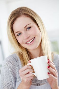She enjoys a refreshing cup of tea. Cute young woman drinking a cup of coffee with a smile.