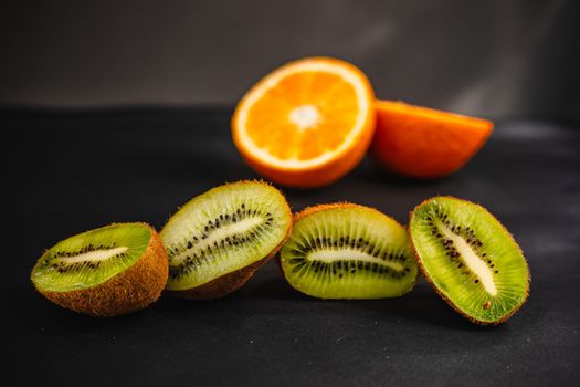 Fresh fruits on a dark background. Orange and kiwi in a cut isolated on a black background. Copy space. high resolution product