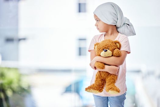 He who has hope, has everything. a little girl standing with her teddy in a clinic.