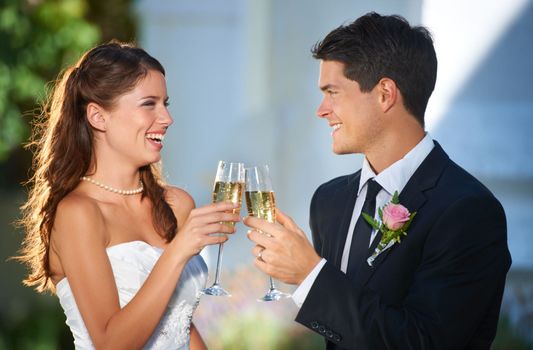 Heres to us and the rest of our lives. two young newlyweds toasting each other with champagne.