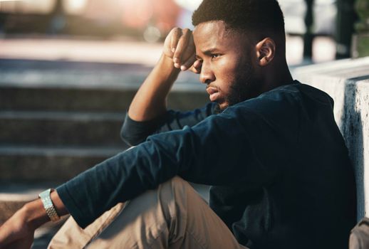 Depressed, angry and black man upset, tired and unhappy outdoor in city, stare and frustrated. Mental health, African American male and young guy with problem, fail and depression being disappointed.