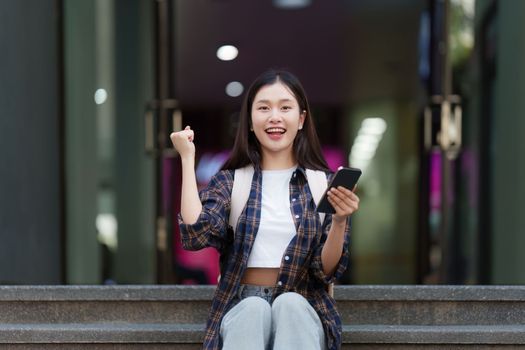 Young Beautiful woman using phone and celebrate while in victory position
