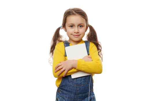 Charming smart schoolchild girl with positive emotions, holding book on white background. Children and education concept