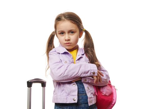Pretty baby girl , preschooler child with two ponytails, posing with backpack and suitcase over white background. Travel