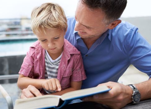 Teaching my son how to read. a father reading to his little boy.