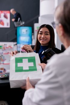 Staisfied asian customer taking drugstore order package at counter