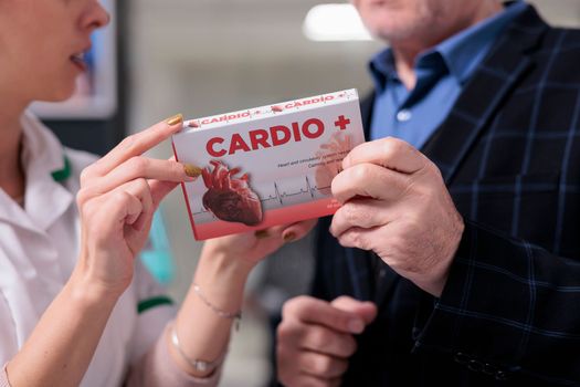 Chemist and man holding heart supplements package in drugstore