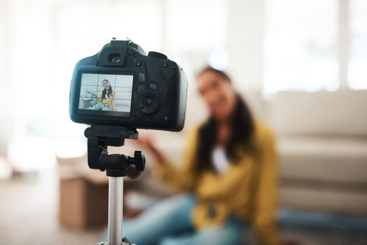 Welcome to the digital age. an attractive young businesswoman sitting in her living room and using her camera to record her vlog.