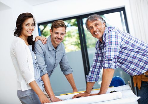 Couple discussing with contractor in office. Portrait of mature contractor with attractive couple smiling in office.