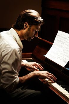 Making beautiful music. Profile of a handsome man playing the piano.