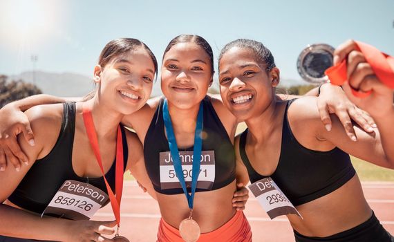 Portrait, diversity and women with medals, for sports and winners on track, smile or victorious together. Champions, healthy girls or athlete happy with results on field, running victory or happiness