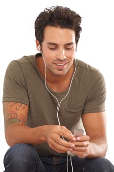 Looking for his favorite track. A handsome young man listening to music on his mp3 player isolated on white.