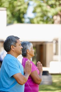 Namaste. Portrait of a mature couple doing yoga together in their backyard
