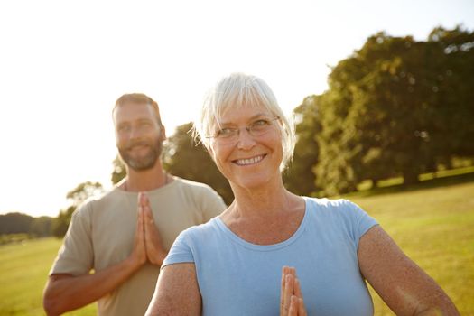 They met each other at a yoga class. a happy mature couple doing yoga together outdoors.
