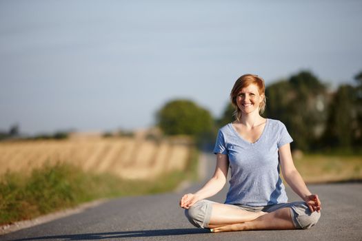 Start the inner journey. Portrait of an attractive woman sitting in the lotus position on a country road.