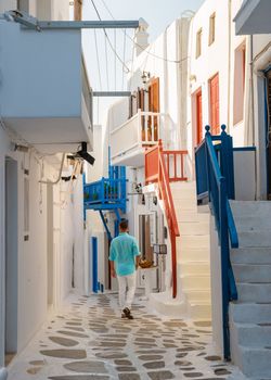 Young men visit Mykonos Greek village in Greece, colorful streets of Mikonos village