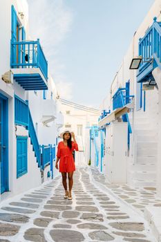 Young women at the street of Mykonos Greek village in Greece, colorful streets of Mikonos village