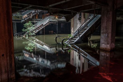 Damaged escalators and waterlogged in abandoned shopping mall building. 