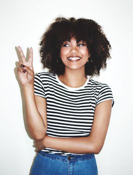 Peace, sign and black woman with smile, excited and casual against a gray studio background. Young female, hand gesture and girl being silly, goofy and playful with trendy, edgy and stylish look.