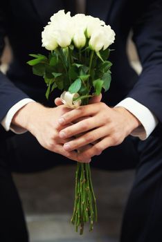 The perfect bunch for the perfect one. A close-up on a mans hands holding a bunch of white roses.