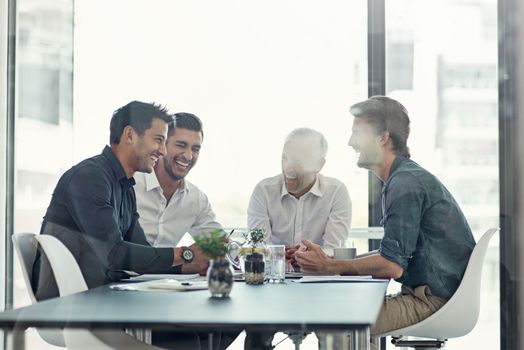 Achieving success together as a team. a group of businessmen having a meeting around a table in an office.