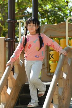 Preschooler asian girl having fun on outdoor playground. Childhood and equipment of entertainment park for kids