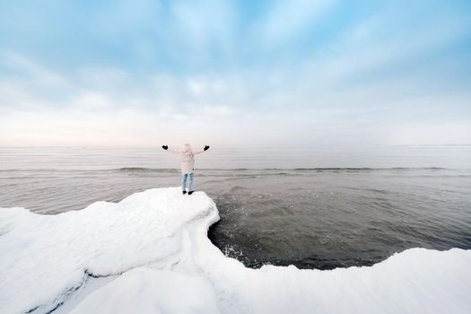 A tourist stands on the shore of the Baltic sea in winter. Winter near the Baltic States of Tallinn.Traveler near the sea in winter