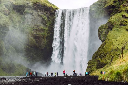 Famous Skogafoss waterfall on Skoga river with crowds of tourists underneath