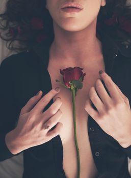 She wants you to stop and smell the roses. High angle shot of an unidentifiable young woman opening her shirt in bed to reveal a rose on her chest.