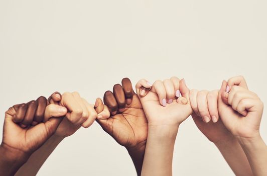 Sticking together. a group of unrecognizable people holding one anothers thumbs in a single line.