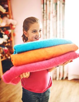 These are my favorite towels. a cheerful little girl carrying a pile of freshly washed towels at home.
