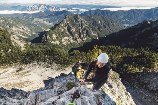 Scenic view of the mountains and woman climber on via ferrata trail in the Alps on a sunny autumn day
