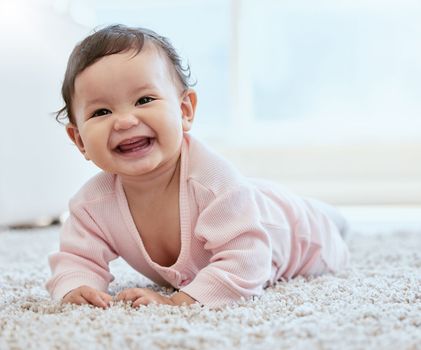 She loves tummy time. an adorable baby girl crawling on the floor at home.