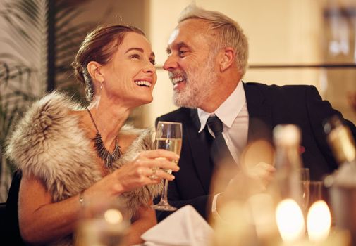 Happy, senior and couple celebration dinner with wine glass and smile of woman with funny man. New years party with mature guests smiling together for joke in elegant, classy and formal style.