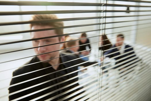 close up. smiling employee looking through office blinds .