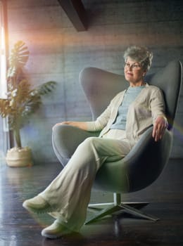 Sophisticated elegant beautiful 50s attractive middle aged smiling woman model sitting in chair looking at camera at home