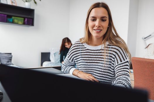 Smiling caucasian woman in stripy sweater doing work on her laptop