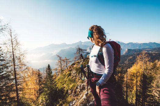 Waist up woman hiker looking away from the camera at a view of the sunny autumn mountains in the background
