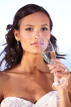 Sparkling wine for her special day. Beautiful young bride holding a glass of champagne.
