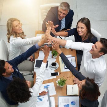 Lets make this our best win yet. High angle shot of a group of businesspeople high fiving together in an office.