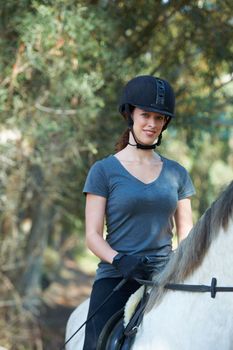 Shes a natural when it comes to horse riding. Portrait of a young woman wearing a helmet and sitting on her horse outside.